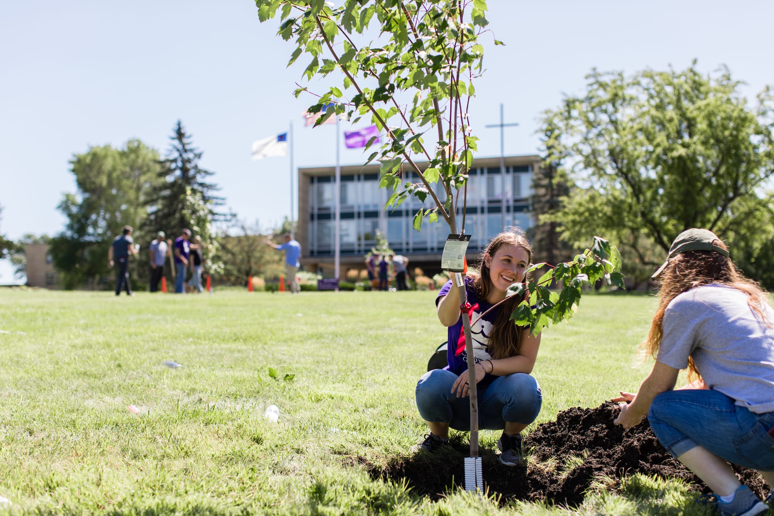 femal students grow a tree in crown college campus